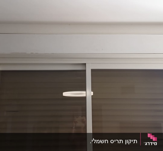 תריסים סגורים על חלון זכוכית עם מסגרת לבנה